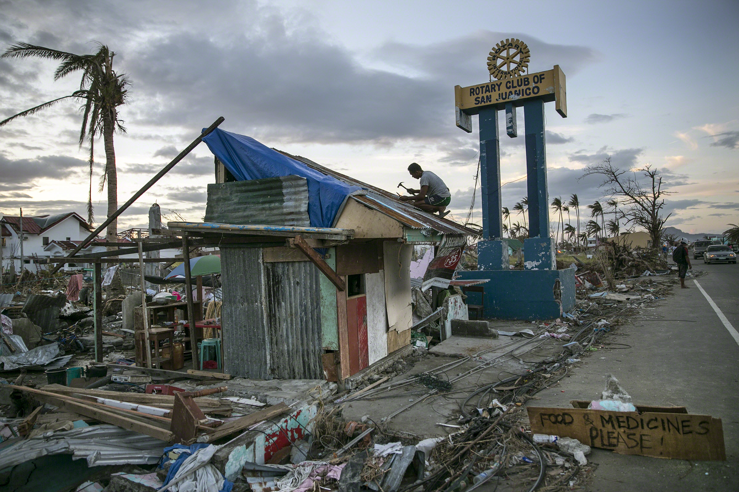 Tacloban, Philippines, 20 November 2013. A man hammers away amidst the destruction caused byTyphoon Haiyan (also known as Yolanda), which hit the islands of Leyte and Samar on 8 November 2013. Photo: Paula Bronstein/Reportage by Getty Images  