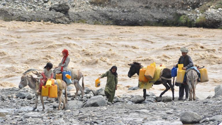 A group of people on donkeys carrying water jugs.