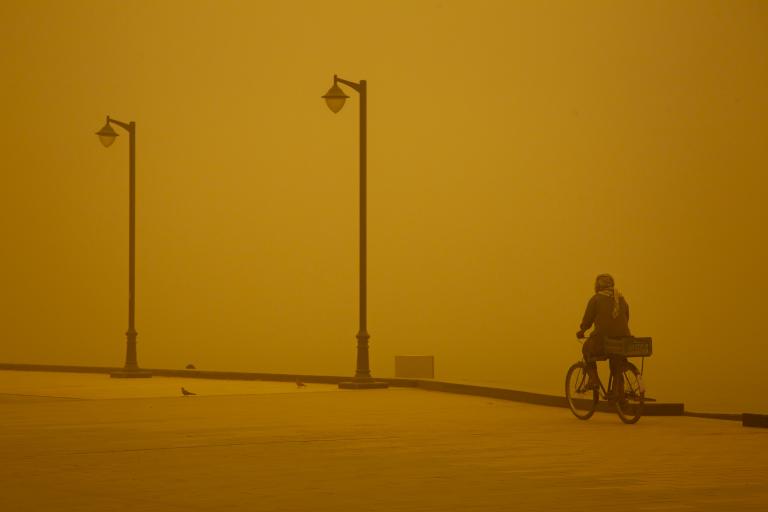 Man cycles in sandstorm in Iraq