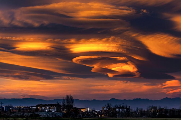 an image of a cloud in the sky with mountains in the background.