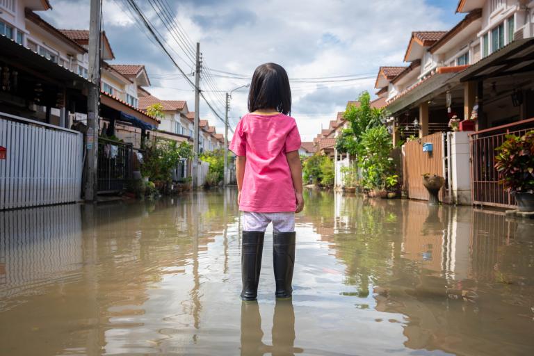 A girl is standing in a flooded street.