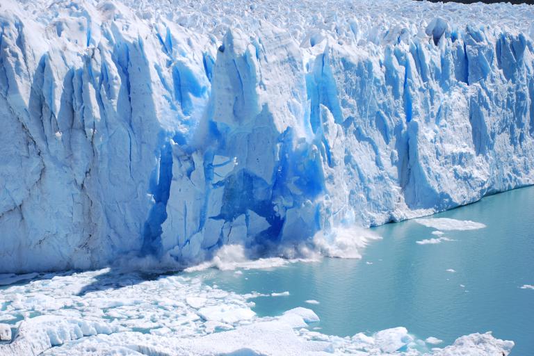 A large glacier with blue ice in the water.
