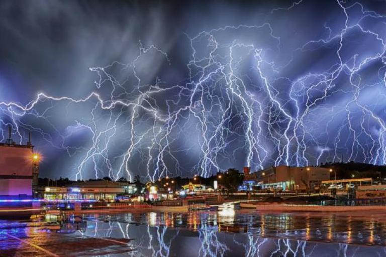 Lightning strikes over a city at night.