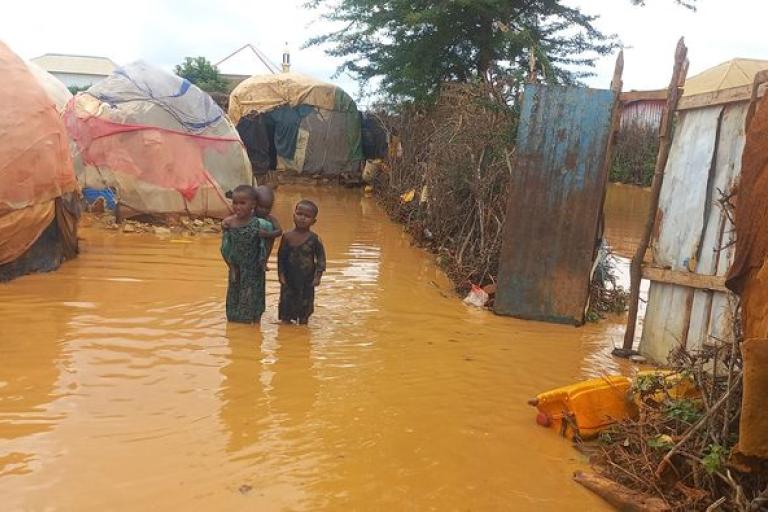 A boy standing in a flooded area near tents.