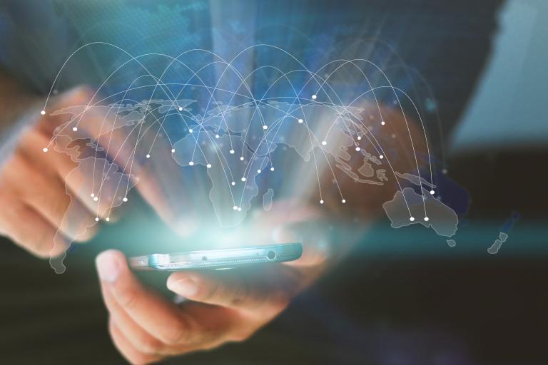Person using a smartphone with graphic representation of global connections superimposed.