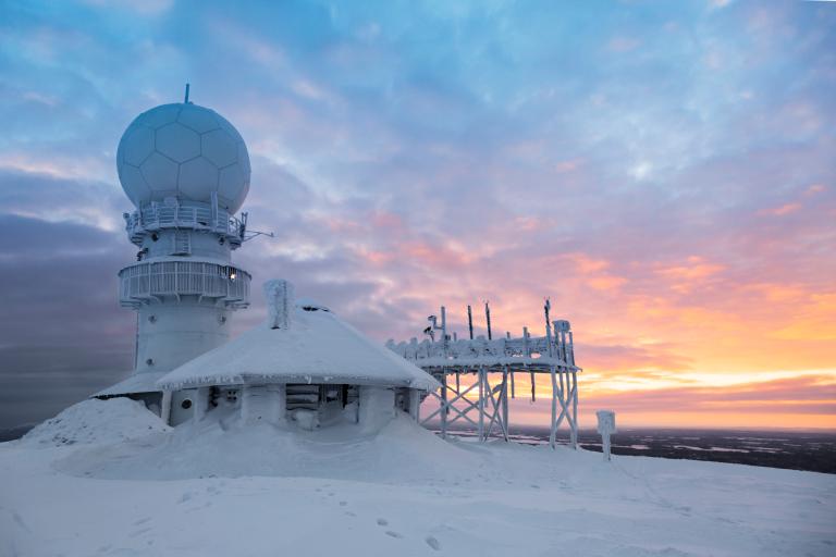A snow covered mountain with a radio tower in the background.