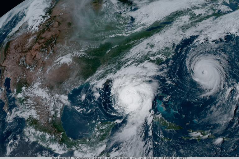 Satellite image showing two hurricanes over the Atlantic Ocean and the Gulf of Mexico, with visible cloud formations and weather patterns over the eastern United States and the Caribbean.