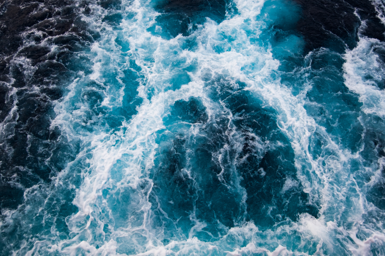 Ariel view of turbulent dark blue ocean waves crashing and foaming.