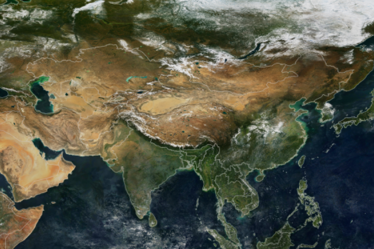 Satellite view of Asia showing diverse landscapes including deserts, mountains, forests, and bodies of water, with snow covering the northern regions.