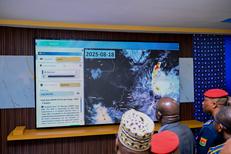 Several uniformed individuals look at a large digital screen displaying weather satellite data and maps dated 2025-08-18.