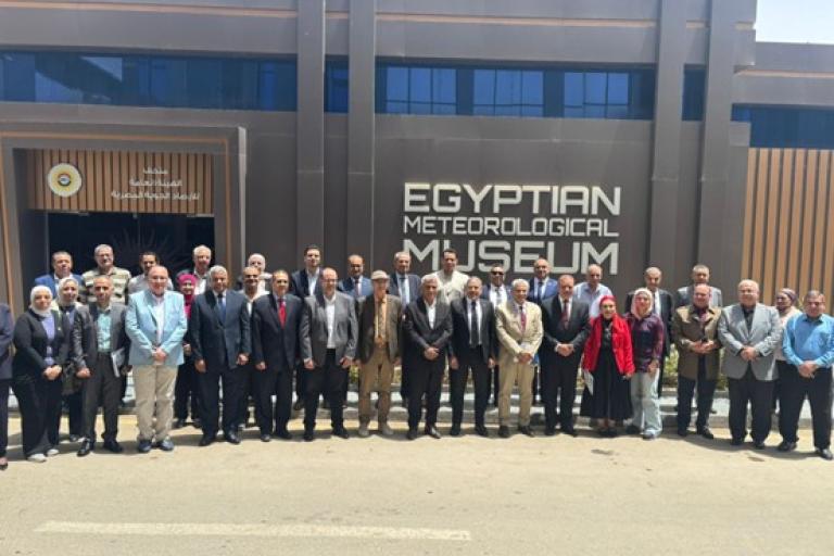 A large group of people stands in front of the Egyptian Meteorological Museum building for a group photo.