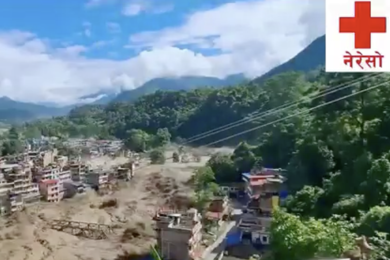A flooded river runs through a town in a mountainous area; damaged buildings and debris are visible. A red cross with Nepali text appears in the top right corner.