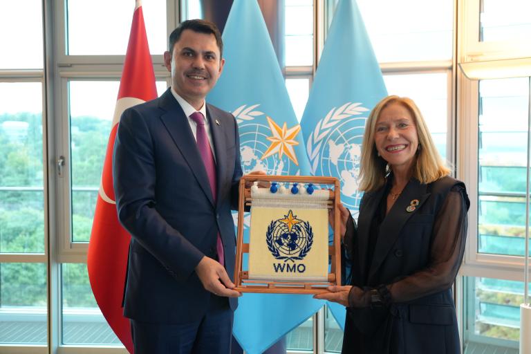 A man and woman stand together holding a WMO plaque, with Turkish and WMO flags visible in the background.