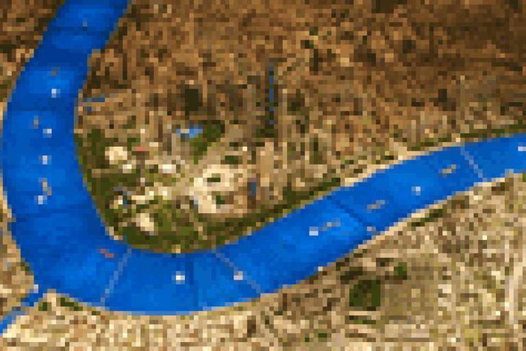 A pixelated aerial view of a city with a wide blue river curving through the landscape, surrounded by urban and green areas.