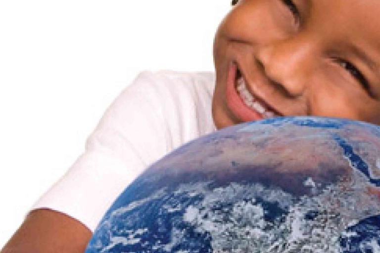 A smiling child in a white shirt hugs a globe, with the child's face and upper body partially visible against a white background.