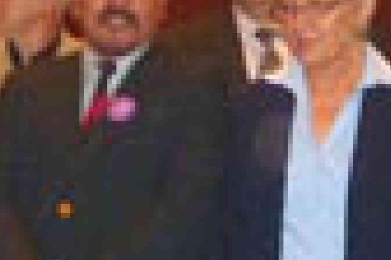 A group of people dressed in business attire stand close together, posing for a formal photograph indoors.