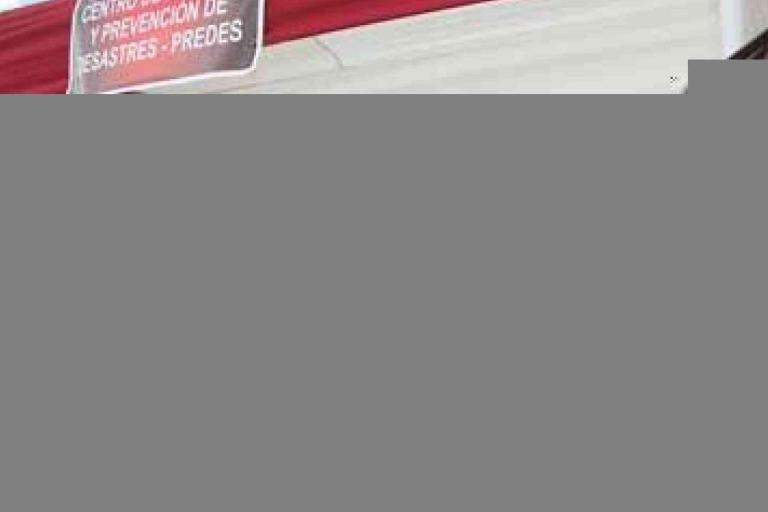 A red and white tent with a sign reading “Centro de Gestión y Prevención de Desastres – PREDDES.” The lower part of the image is partially obscured.