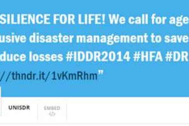 Blue banner with white text promoting age-inclusive disaster management, featuring hashtags #IDDR2014, #HFA, #DRR, and a shortened URL link.