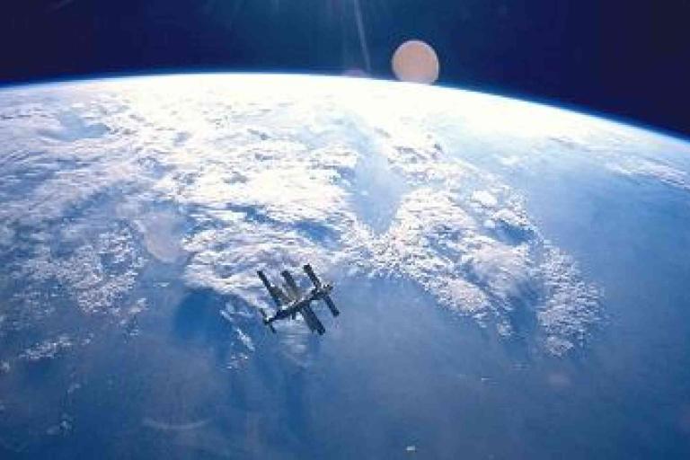 A large spacecraft orbits above Earth's surface, with clouds and blue atmosphere visible in the background.