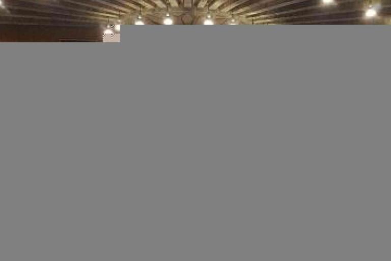 A symmetrical ceiling with a radial wooden beam design and multiple round lights arranged in a circular pattern.