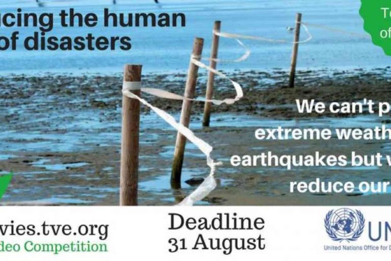 Banner promoting a video competition on reducing disaster costs, featuring warning tape on wooden posts, competition deadline, and UNISDR logo.