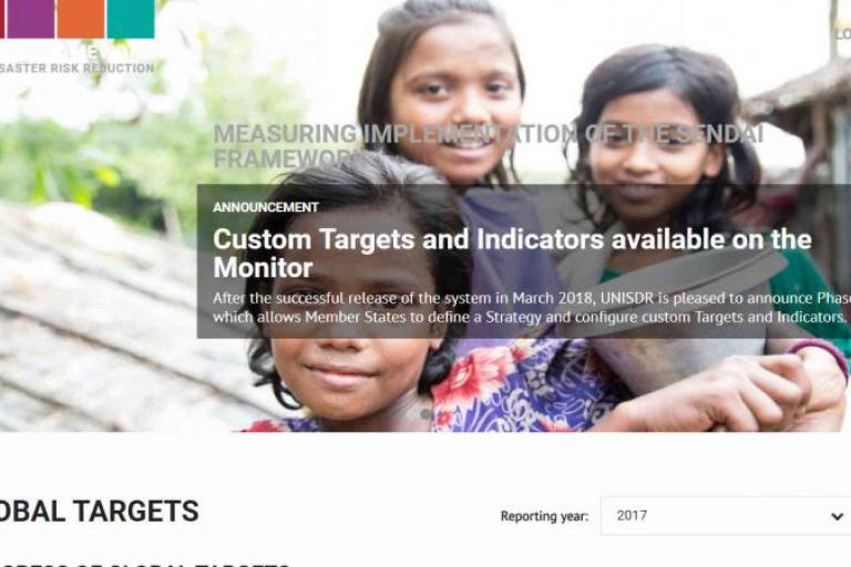 Three children smile at the camera outdoors, with text overlay announcing the availability of custom targets and indicators on the UNISDR Sendai Framework Monitor.