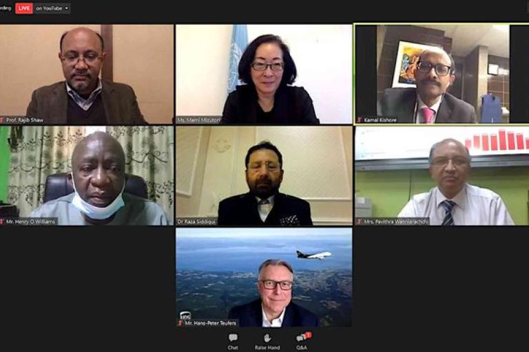 A screenshot of a virtual meeting with seven participants, each visible in their individual video frames against various backgrounds.