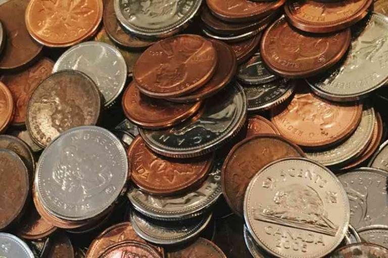 A close-up of assorted Canadian coins, including pennies, nickels, and dimes, scattered and overlapping each other.