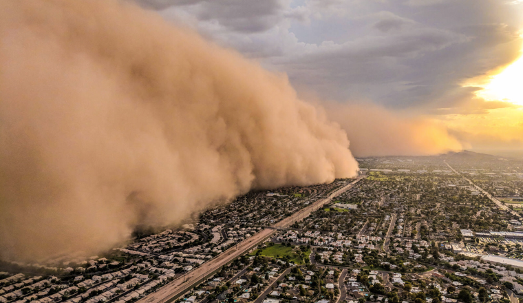 A huge cloud of sand blows over a city.