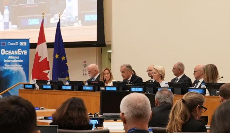 Panel of officials seated at a conference table, with Canadian and EU flags behind them, and an “Ocean Eye” banner visible on the left side of the image.