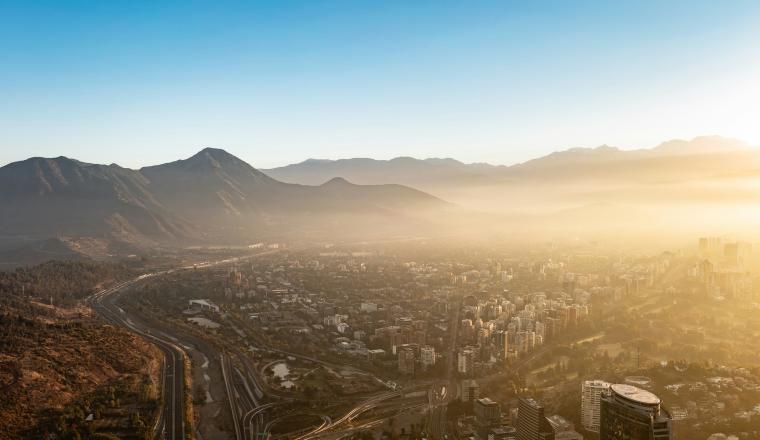 Aerial view of a city nestled in a valley surrounded by mountains at sunrise.