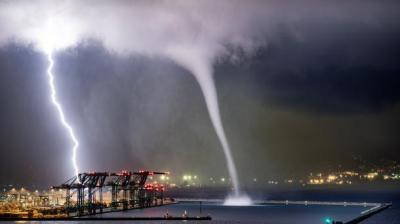 Lightning and water spout over brightly lit industrial area