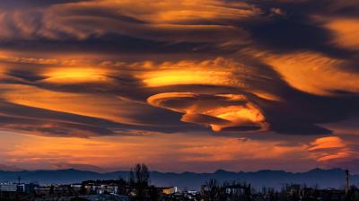 an image of a cloud in the sky with mountains in the background.