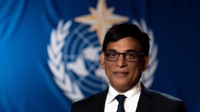 Alok Kumar Ojha standing in front of WMO flag.
