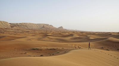 a man is walking across a desert in a sand dune.