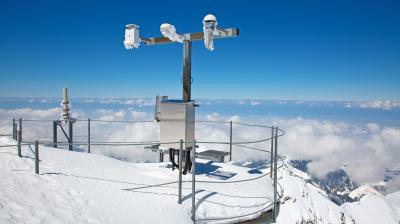 A weather station on top of a snow covered mountain.