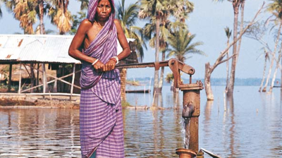 A woman in a sari standing next to a water pump.