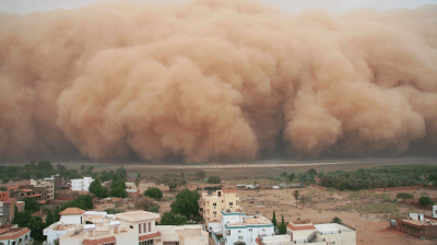 A large cloud of dust is seen over a city.