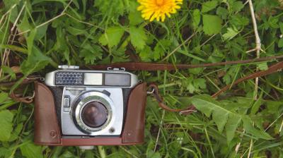 An old camera sitting in the grass.