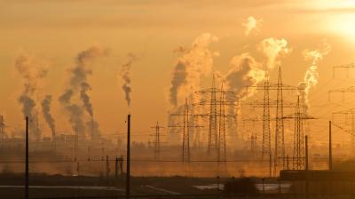 Smoke rises from a power plant at sunset.