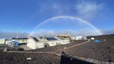 A rainbow is seen over a building with solar panels.