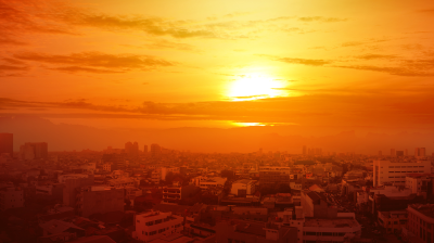 Sunrise over a cityscape with buildings silhouetted against a vibrant orange sky.