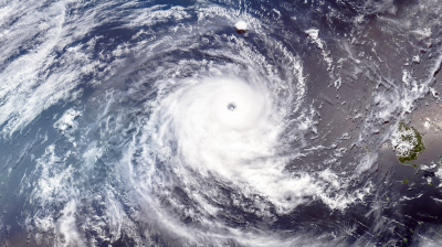 Satellite view of a large hurricane over the ocean with distinct eye and spiraling cloud bands.