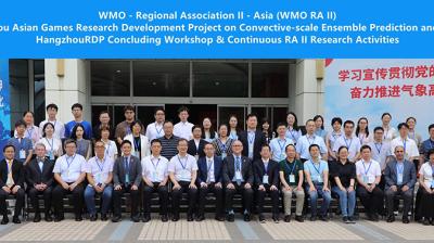 Group photo of conference attendees standing and seated in front of a banner for the 19th Hangzhou Asian Games research project and related workshops.