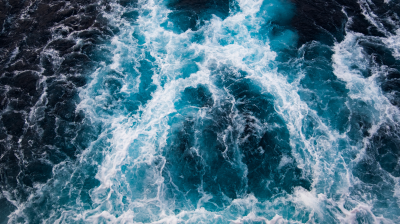 Ariel view of turbulent dark blue ocean waves crashing and foaming.