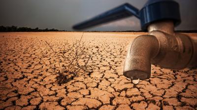 A dry, cracked landscape with a single dried plant and a close-up of a faucet with a single droplet of water, symbolizing drought and water scarcity.