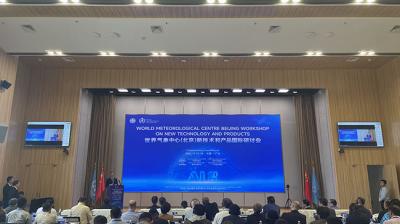 Conference room with people attending the World Meteorological Centre Beijing Workshop on new technology and products. Large screen displays workshop details.