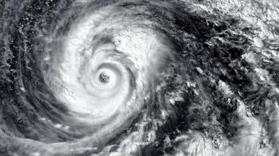 Satellite image of a swirling hurricane with a distinct eye at the center, surrounded by dense cloud formations.
