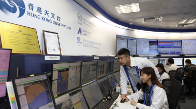 Meteorologists at the Hong Kong Observatory monitor weather data and forecasts on multiple computer screens in a control room.
