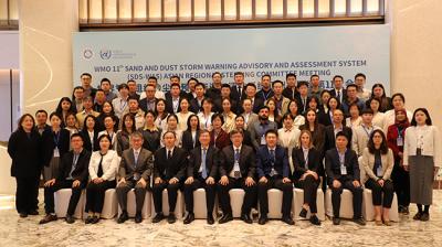 A large group of people in business attire pose for a group photo at the WMO 11th Sand and Dust Storm Warning Advisory and Assessment System meeting.
